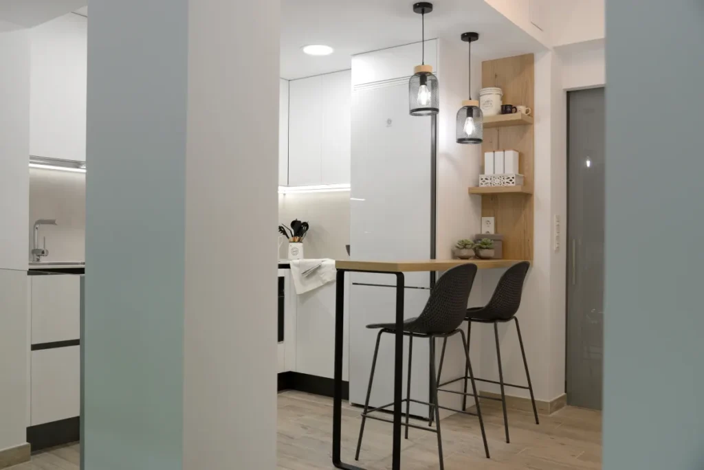 Cocina reformada abierta al pasillo, con muebles blancos y distribución en L.
