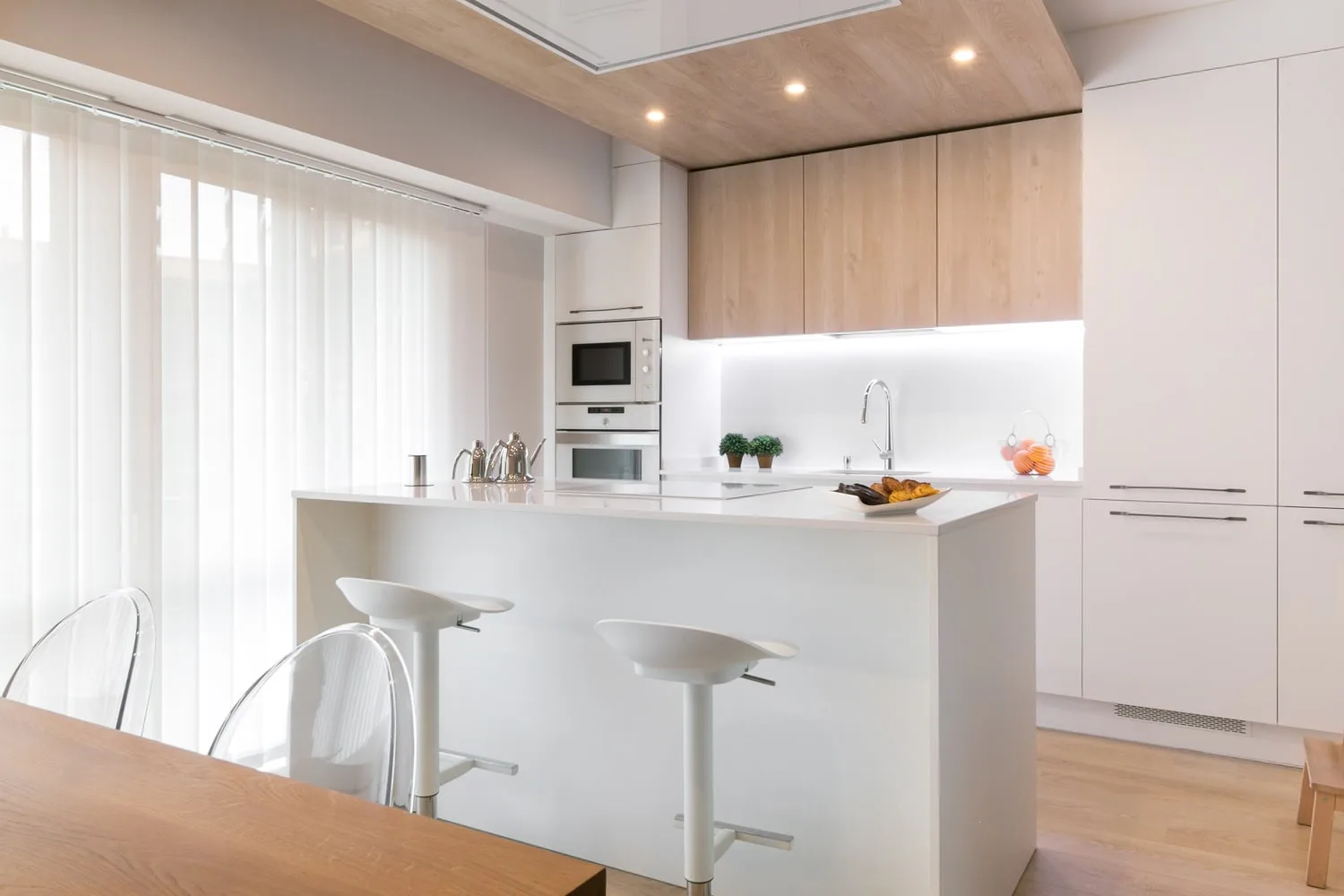 cocina blanca con muebles altos madera y techo revestido madera